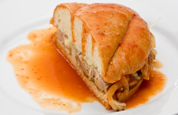 Mexican Torta Ahogada, or drowned sandwich with pork on a white plate.